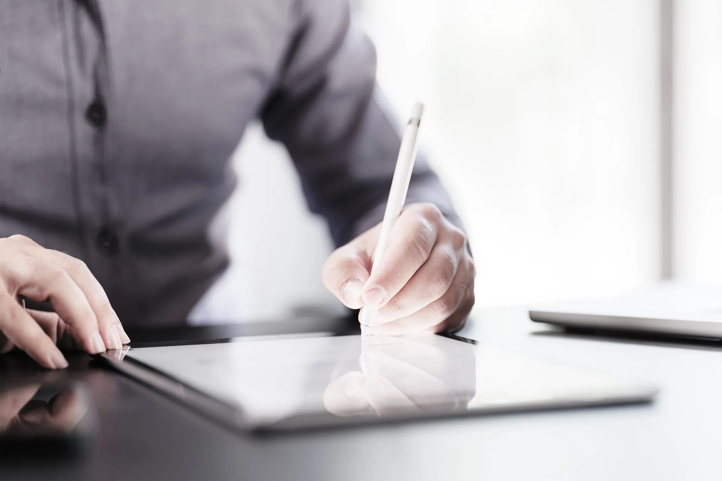 Person, die mit einem Stift auf einem Tablet arbeitet.